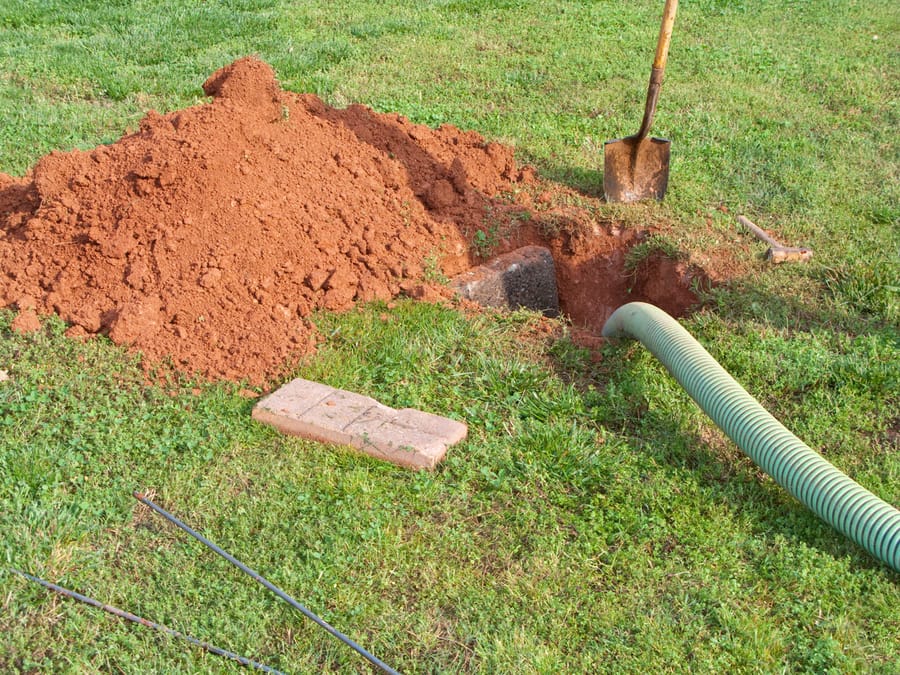 Open septic tank in the yard during a septic tank pumping service.