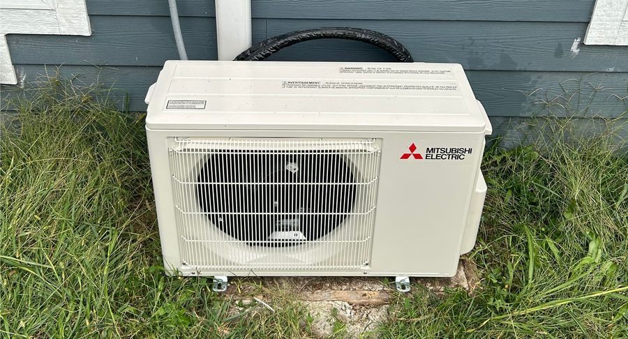 Up close image of a ductless mini-split sitting outside home.