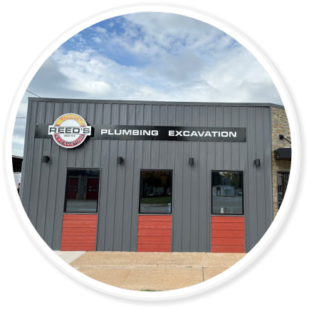 a front of a commercial building in grey with red siding accents and a Reeds logo sign on the front
